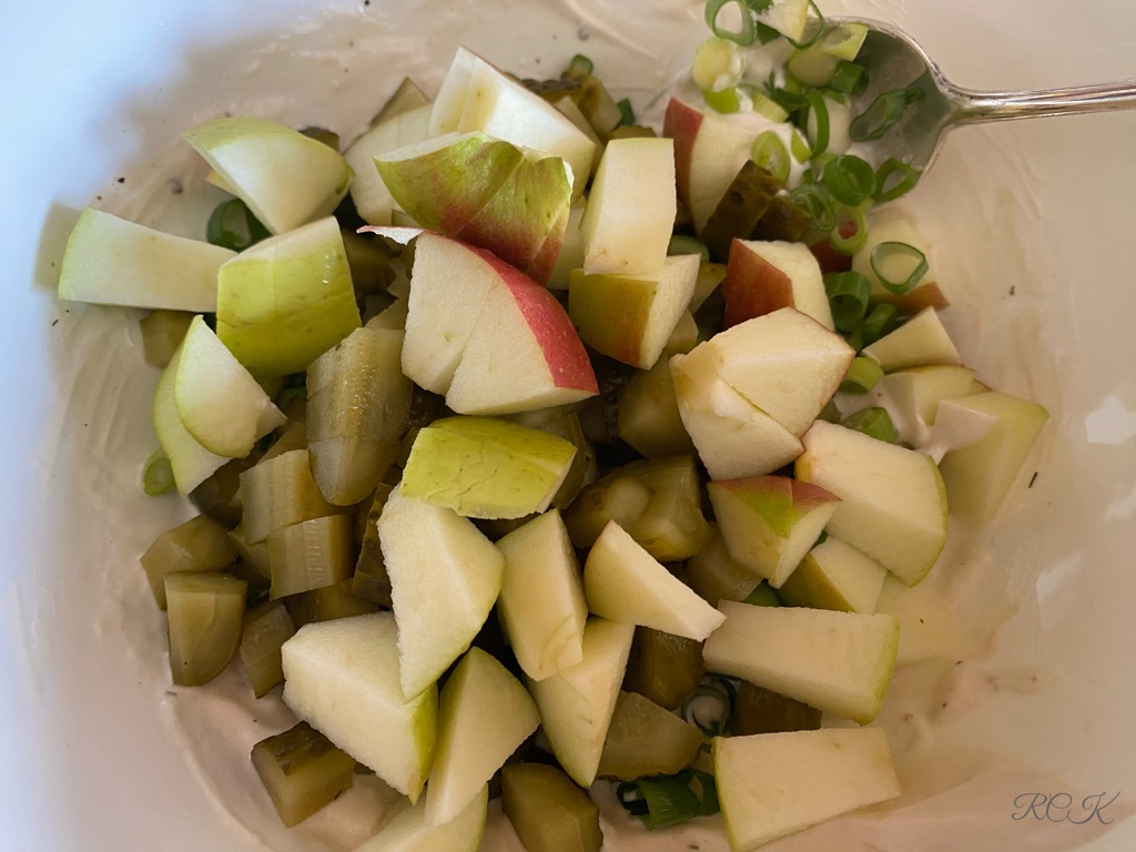Äpfel, Gewürzgurken, Frühlingszwiebeln den Tahina-Dressing hinzufügen